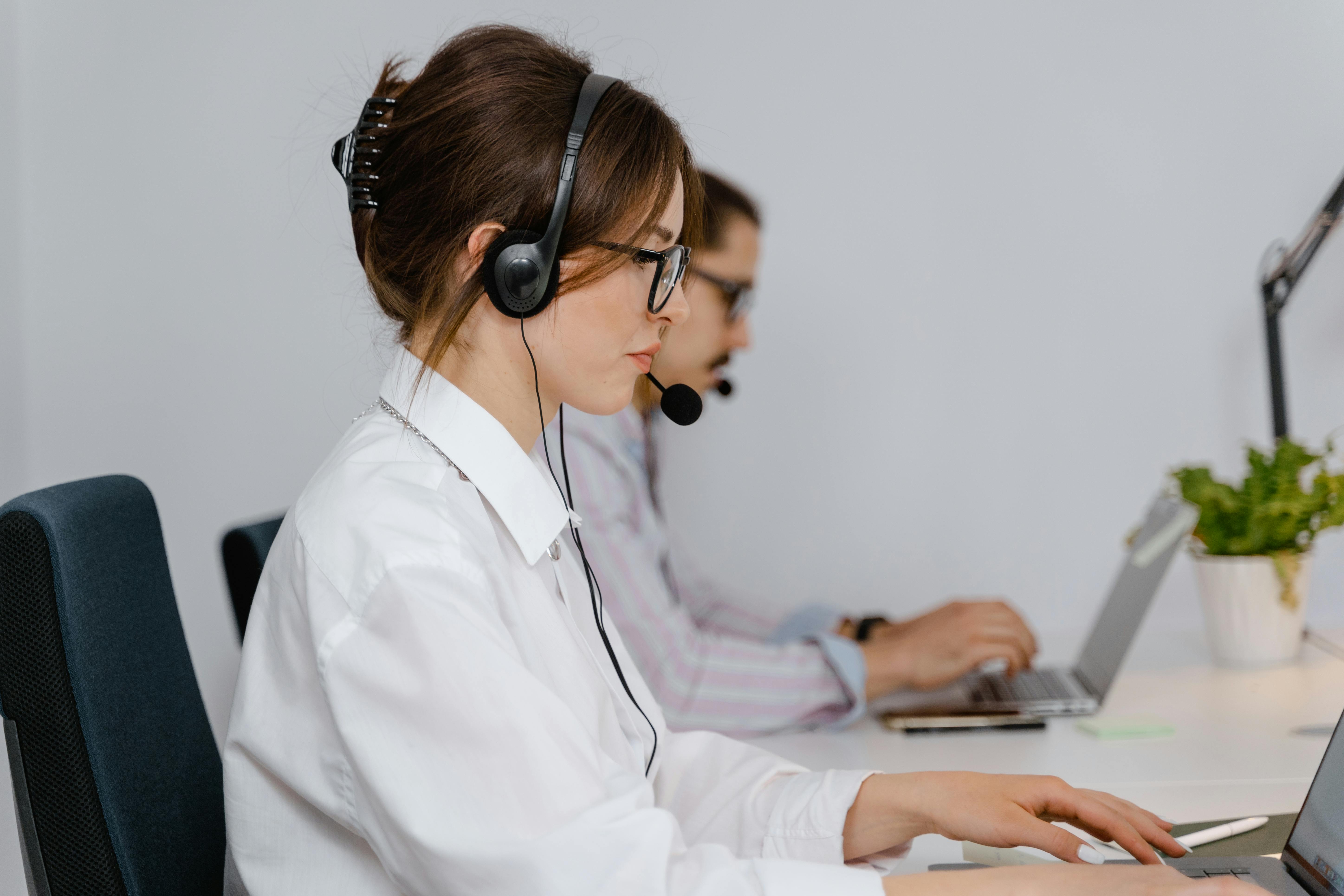 Two People With Headsets and Laptops